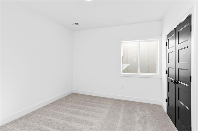 carpeted spare room with visible vents and baseboards