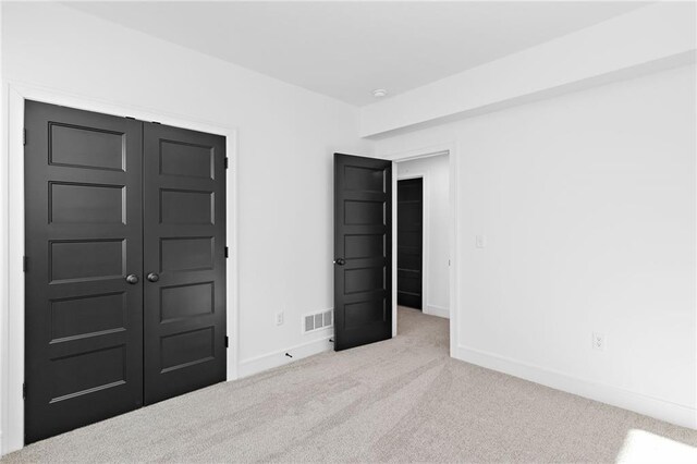 unfurnished bedroom featuring light carpet and a closet