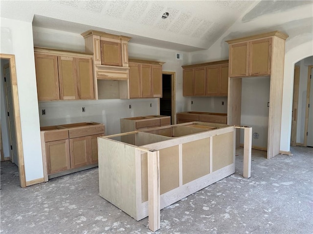 kitchen featuring lofted ceiling, a kitchen island, and arched walkways