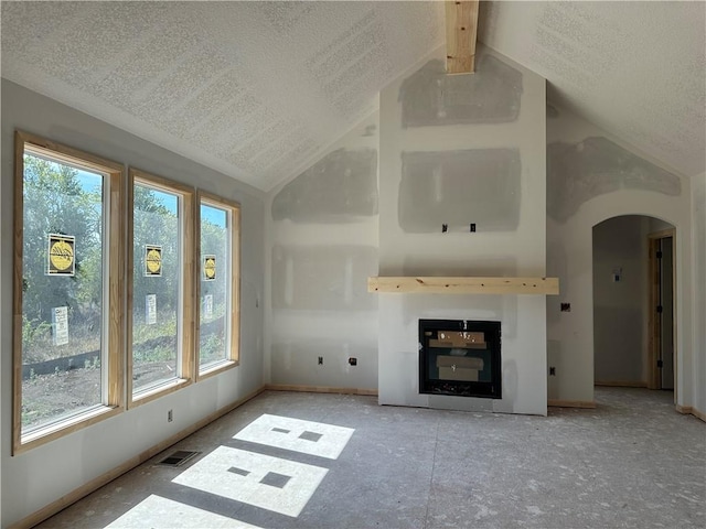 unfurnished living room with plenty of natural light, visible vents, lofted ceiling, and arched walkways
