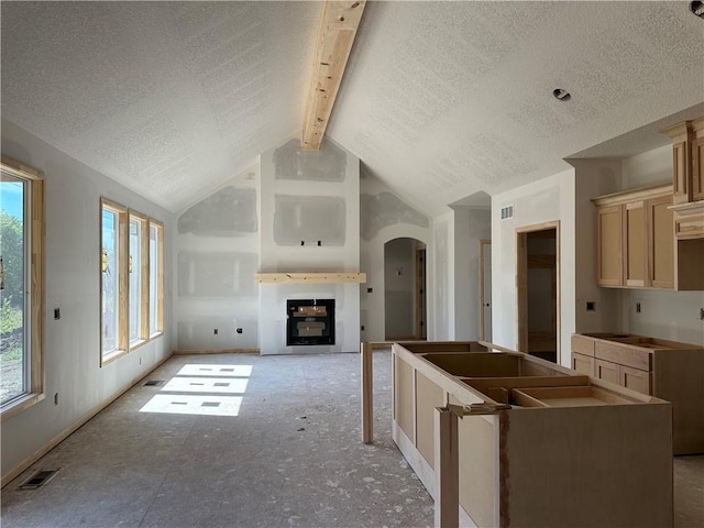 kitchen featuring arched walkways, a fireplace, visible vents, and a textured ceiling