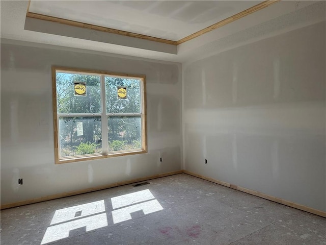empty room featuring baseboards, a tray ceiling, visible vents, and plenty of natural light