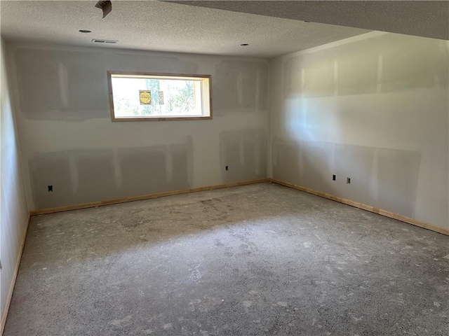unfurnished room with a textured ceiling, visible vents, and baseboards