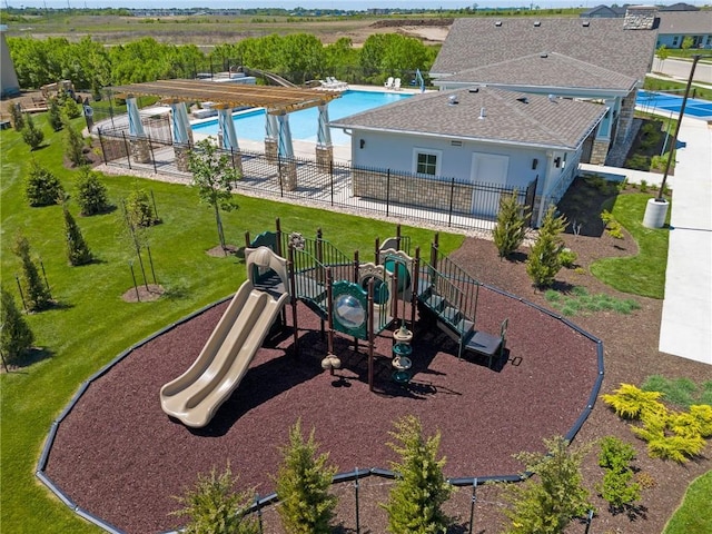 community jungle gym with a yard, fence, and a community pool