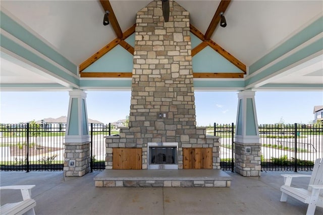 view of patio with an outdoor stone fireplace and fence