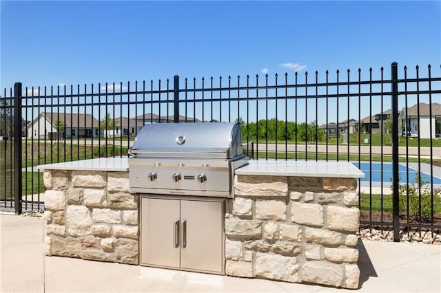 view of patio / terrace with fence, exterior kitchen, and a grill