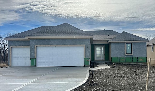 view of front of home featuring a garage, driveway, a shingled roof, and stucco siding