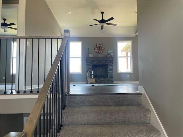 staircase featuring wood-type flooring, ceiling fan, and a fireplace