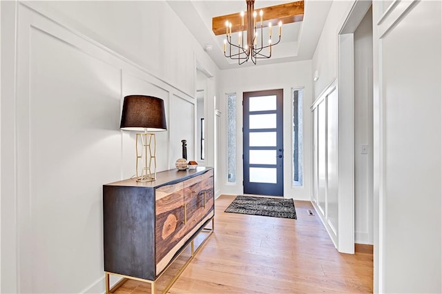 foyer entrance with beamed ceiling, a notable chandelier, and light wood-type flooring