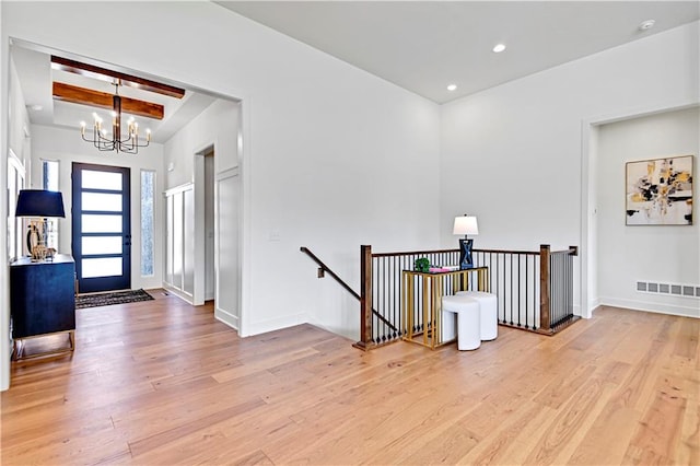 foyer with beam ceiling, an inviting chandelier, and light hardwood / wood-style flooring