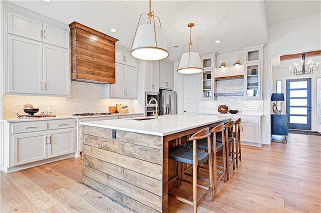 kitchen featuring a center island with sink, white cabinets, and hanging light fixtures