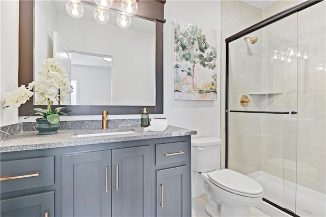 bathroom featuring a shower with door, vanity, and toilet