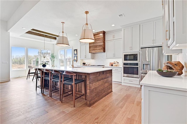 17433 Gillette St, Overland Park, KS 66221 - kitchen featuring stainless steel appliances, a sink, a center island with sink, light countertops, and light wood finished floors
