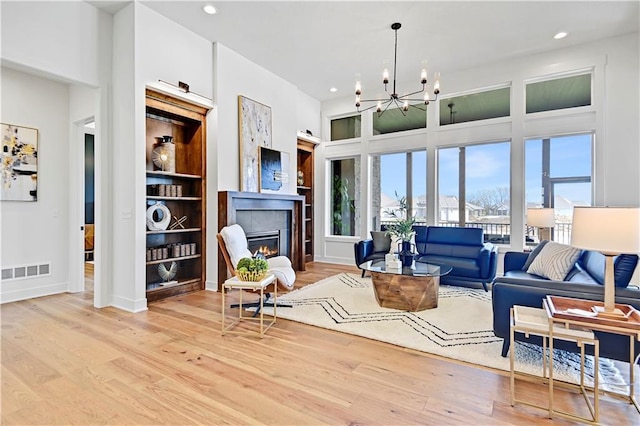 17433 Gillette St, Overland Park, KS 66221 - living room with a chandelier, light wood-style flooring, a lit fireplace, recessed lighting, and baseboards
