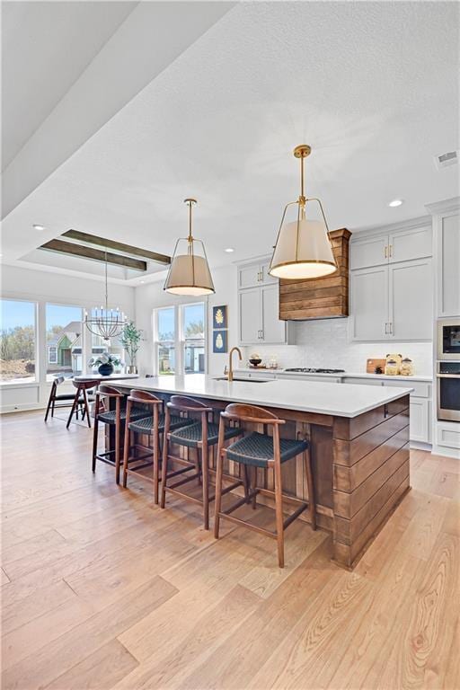 17433 Gillette St, Overland Park, KS 66221 - kitchen with light wood-type flooring, light countertops, decorative backsplash, a large island with sink, and recessed lighting