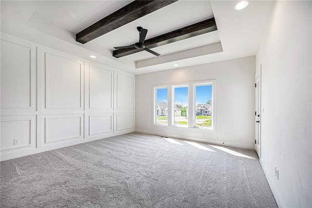 carpeted spare room featuring ceiling fan, beam ceiling, and a tray ceiling