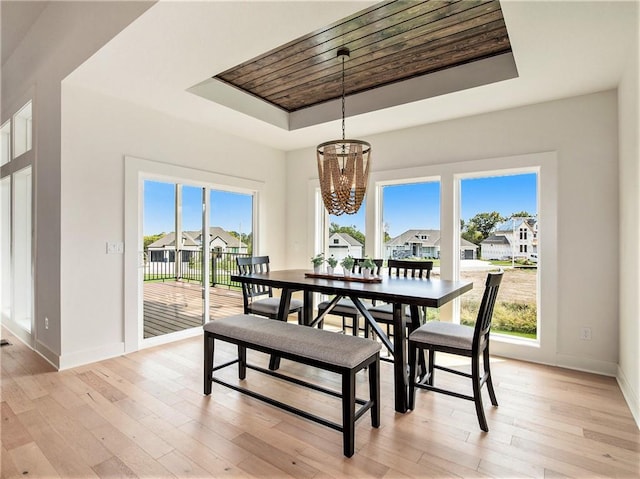 dining room featuring a tray ceiling, a chandelier, and light hardwood / wood-style flooring