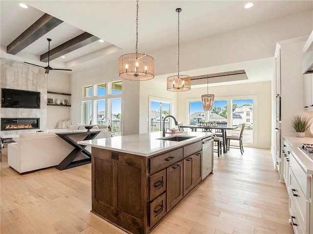 kitchen featuring white cabinetry, sink, hanging light fixtures, and a center island with sink