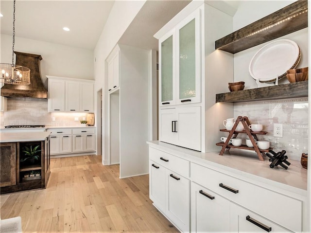 bar with decorative light fixtures, decorative backsplash, white cabinets, and light wood-type flooring