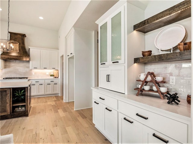 kitchen featuring tasteful backsplash, light wood-type flooring, light countertops, and white cabinetry