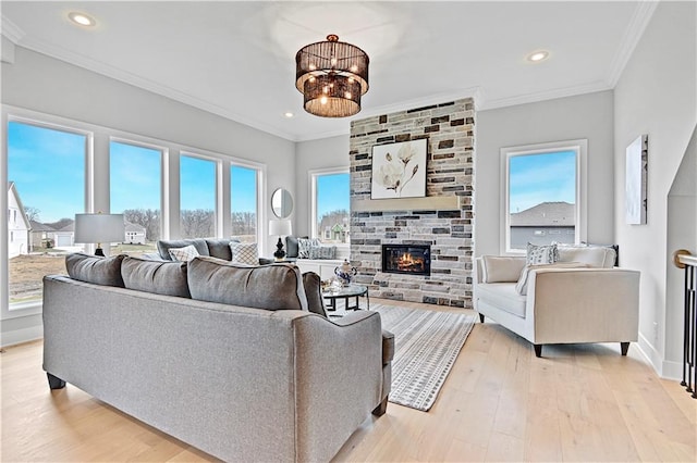 living room with a stone fireplace, crown molding, light hardwood / wood-style flooring, and a notable chandelier