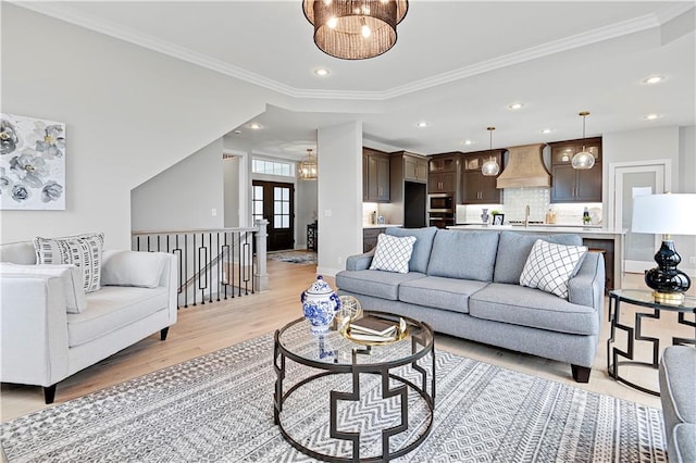 living room featuring light hardwood / wood-style floors, sink, and crown molding