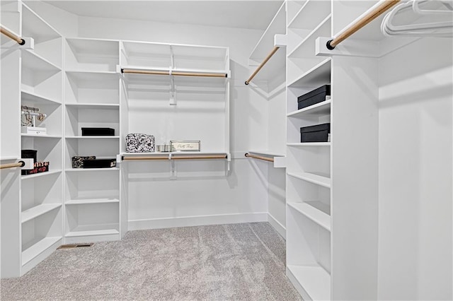 walk in closet featuring light colored carpet