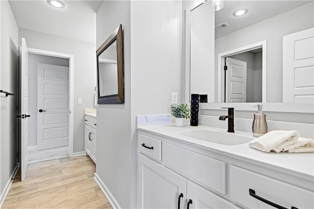 bathroom with a textured ceiling, vanity, and hardwood / wood-style flooring