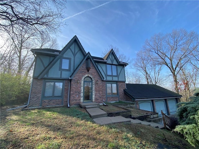 tudor home with brick siding, a front yard, and stucco siding