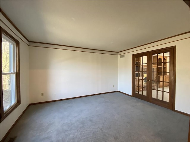 carpeted spare room with ornamental molding, french doors, plenty of natural light, and baseboards