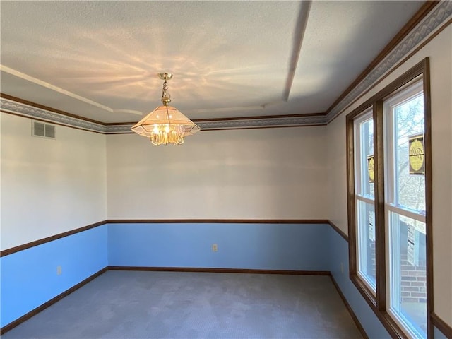 empty room featuring carpet floors, visible vents, ornamental molding, a textured ceiling, and baseboards