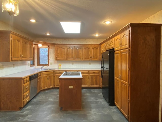 kitchen featuring brown cabinets, light countertops, stainless steel dishwasher, freestanding refrigerator, and a kitchen island