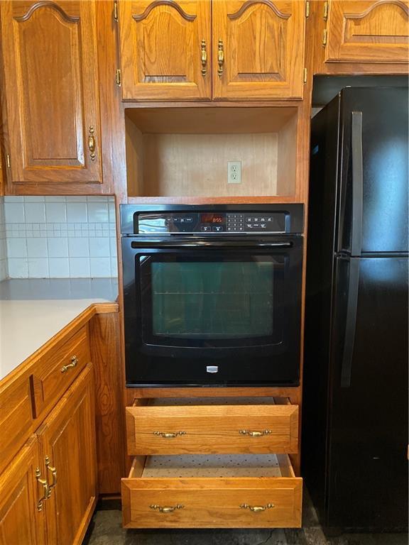 kitchen featuring black appliances, brown cabinets, backsplash, and light countertops