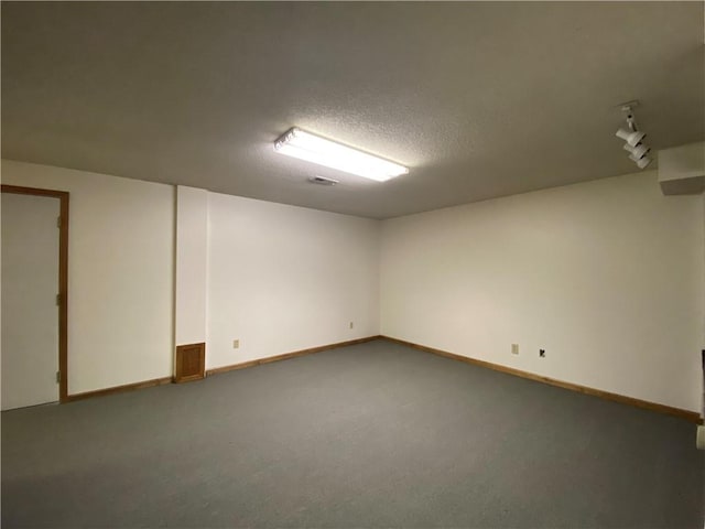 finished below grade area with carpet, baseboards, and a textured ceiling