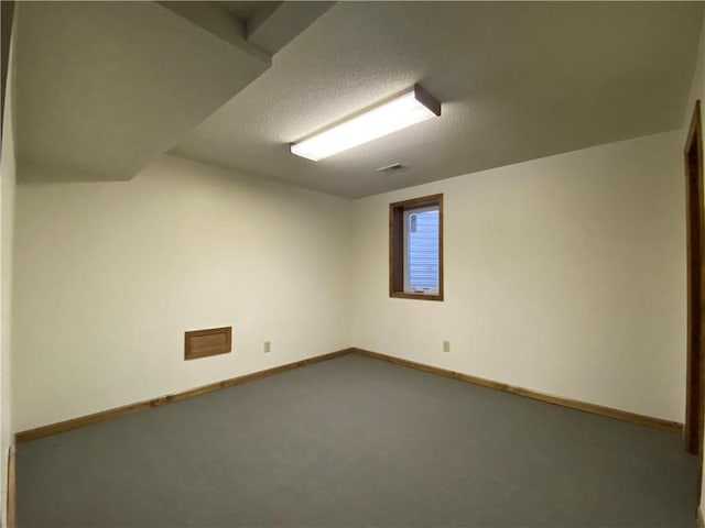 spare room with a textured ceiling, carpet floors, visible vents, and baseboards