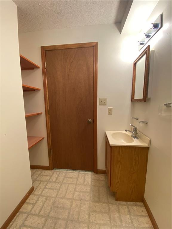 bathroom with vanity, a textured ceiling, baseboards, and tile patterned floors