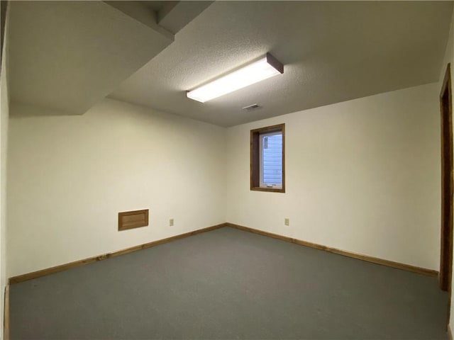 spare room featuring carpet, a textured ceiling, and baseboards