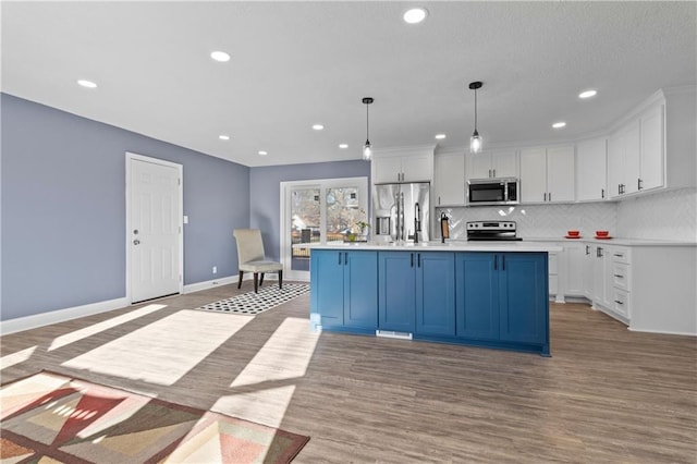 kitchen with white cabinets, an island with sink, stainless steel appliances, and decorative light fixtures