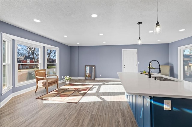 living room featuring a textured ceiling, sink, and light wood-type flooring