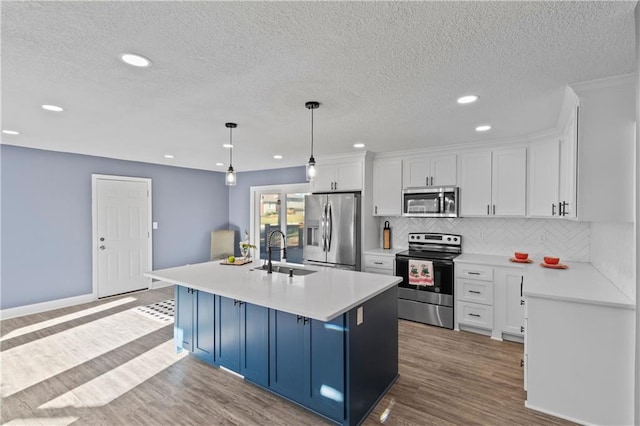 kitchen with white cabinets, stainless steel appliances, light wood-type flooring, pendant lighting, and sink