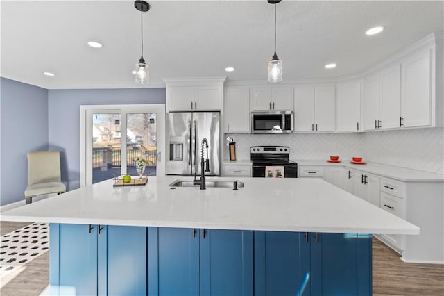 kitchen with pendant lighting, a center island with sink, appliances with stainless steel finishes, and white cabinetry