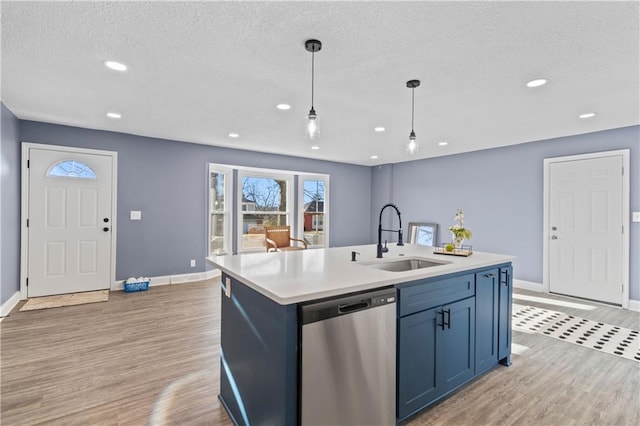 kitchen with a kitchen island with sink, sink, light wood-type flooring, dishwasher, and pendant lighting