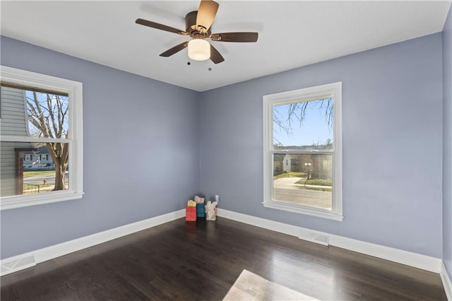 unfurnished room featuring ceiling fan, dark hardwood / wood-style floors, and a wealth of natural light