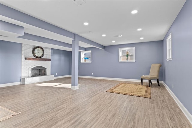 unfurnished room featuring light hardwood / wood-style flooring, brick wall, and a brick fireplace