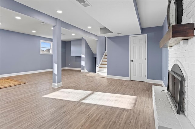 basement featuring a brick fireplace and light wood-type flooring