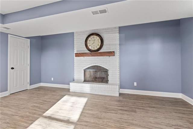 unfurnished living room with brick wall, a fireplace, and dark wood-type flooring