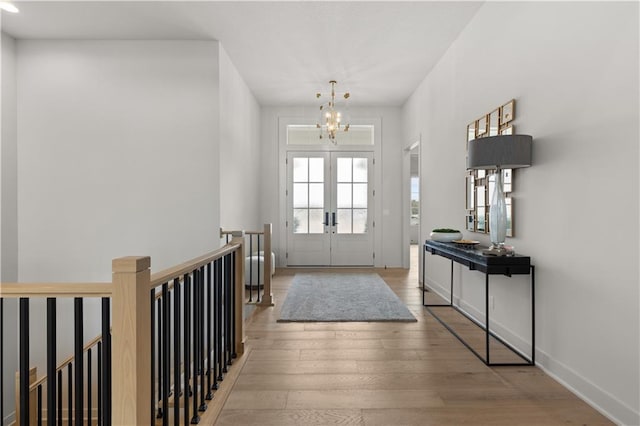 foyer with an inviting chandelier, light hardwood / wood-style floors, and french doors