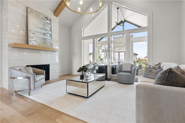 living room with hardwood / wood-style floors, beam ceiling, high vaulted ceiling, a notable chandelier, and a large fireplace