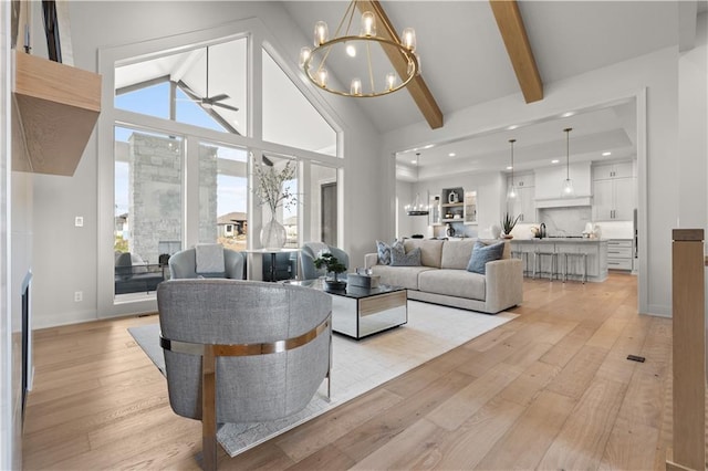 living room featuring ceiling fan with notable chandelier, sink, light hardwood / wood-style floors, and lofted ceiling with beams