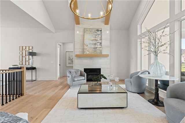 living room featuring light hardwood / wood-style flooring, a large fireplace, a chandelier, and vaulted ceiling